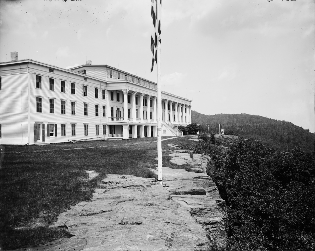 The Catskill Mountain House around 1900-1910, its long columned front on the edge of the escarpment, in a black and white photograph.
