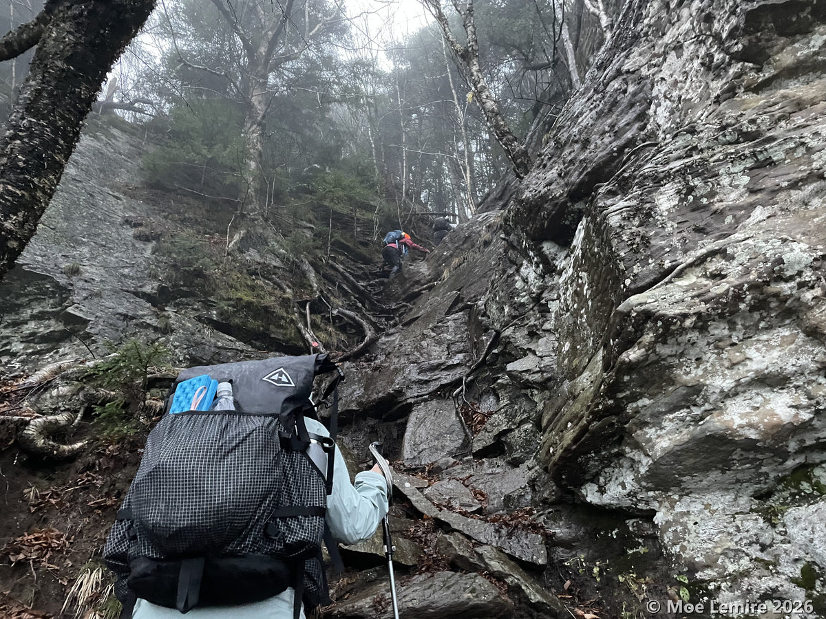 Hikers scrambling up rock on Indian Head Mountain